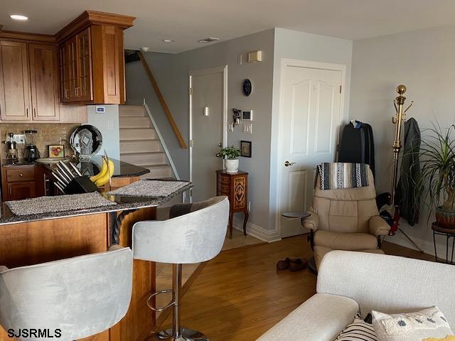 interior space with tasteful backsplash, light hardwood / wood-style flooring, and a kitchen bar