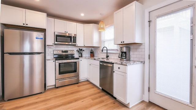 kitchen featuring appliances with stainless steel finishes, decorative light fixtures, sink, and white cabinets