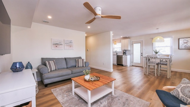 living room featuring sink, light hardwood / wood-style flooring, and ceiling fan