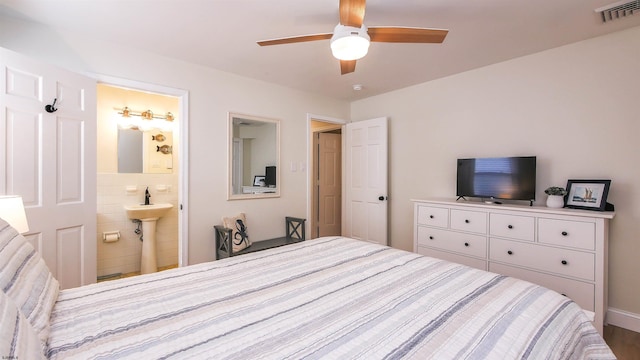 bedroom featuring ensuite bathroom, sink, and ceiling fan