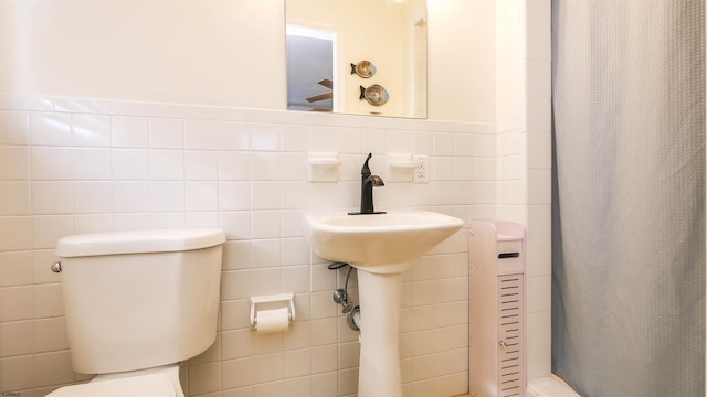 bathroom featuring toilet, a shower with shower curtain, and tile walls