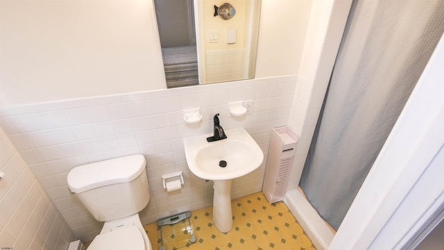 bathroom featuring a shower with curtain, toilet, and tile walls