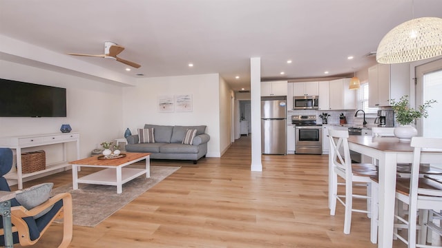 living room featuring ceiling fan, sink, and light hardwood / wood-style flooring