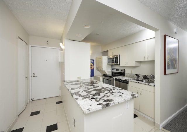 kitchen featuring appliances with stainless steel finishes, sink, white cabinets, and a textured ceiling