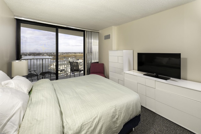 carpeted bedroom with expansive windows and a textured ceiling