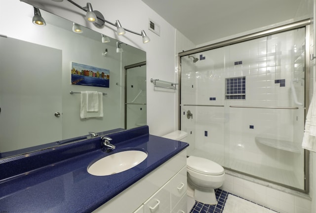 bathroom featuring vanity, a shower with shower door, tile patterned floors, and toilet