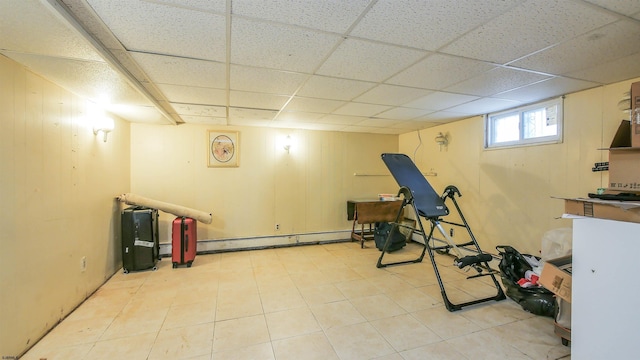 exercise room with baseboard heating, a paneled ceiling, and wood walls