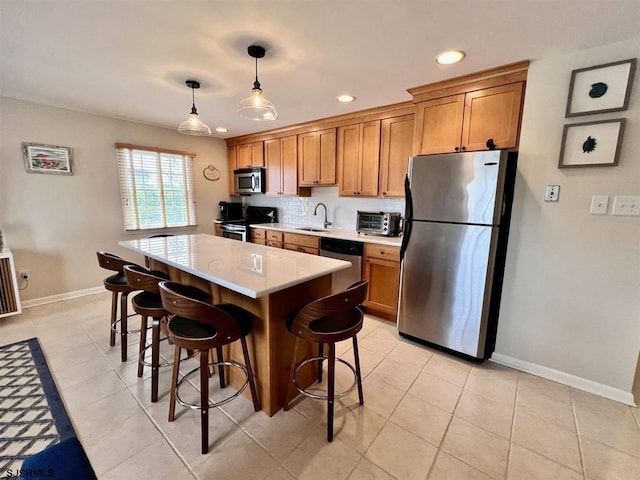 kitchen with a kitchen island, decorative light fixtures, sink, a breakfast bar area, and stainless steel appliances