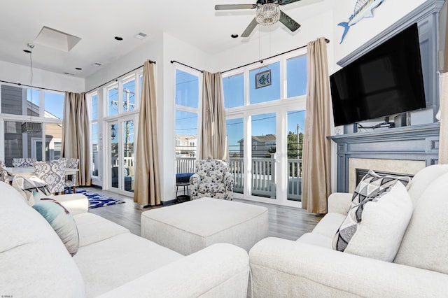 living room with ceiling fan, wood-type flooring, a fireplace, and a wealth of natural light