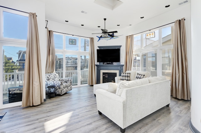 living room featuring ceiling fan, light hardwood / wood-style flooring, and a healthy amount of sunlight