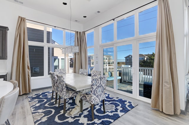 dining space featuring a towering ceiling and light hardwood / wood-style floors