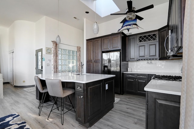 kitchen featuring a towering ceiling, a kitchen island with sink, hanging light fixtures, and backsplash