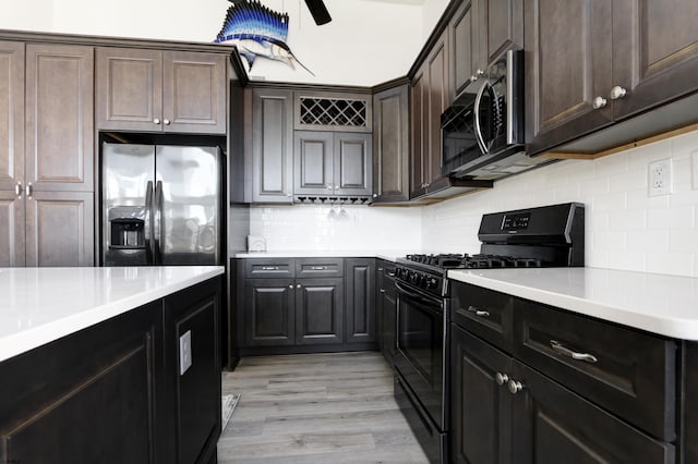 kitchen featuring dark brown cabinetry, appliances with stainless steel finishes, light hardwood / wood-style floors, and backsplash