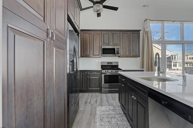 kitchen featuring sink, appliances with stainless steel finishes, dark brown cabinets, light hardwood / wood-style floors, and decorative backsplash