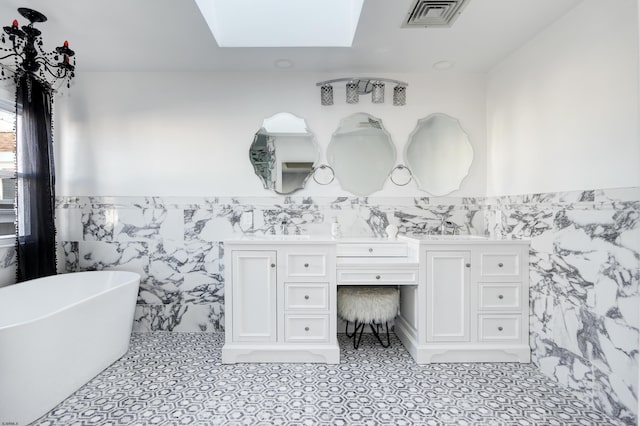 bathroom featuring vanity, a washtub, tile walls, and a skylight