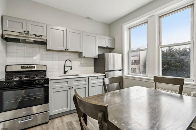 kitchen featuring sink, backsplash, light hardwood / wood-style flooring, and stainless steel appliances