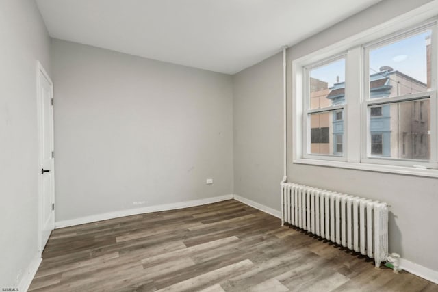 unfurnished room with radiator heating unit and dark hardwood / wood-style flooring