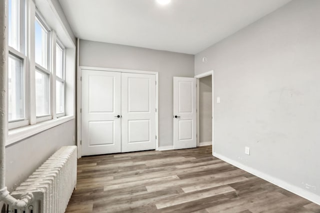 bedroom with radiator heating unit, light hardwood / wood-style floors, and a closet