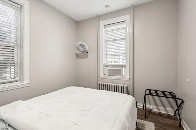 bedroom with multiple windows, wood-type flooring, radiator, and cooling unit