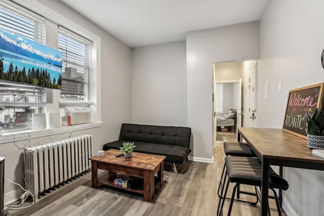 living room with radiator, cooling unit, and light hardwood / wood-style floors