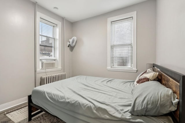 bedroom featuring cooling unit, radiator heating unit, and wood-type flooring