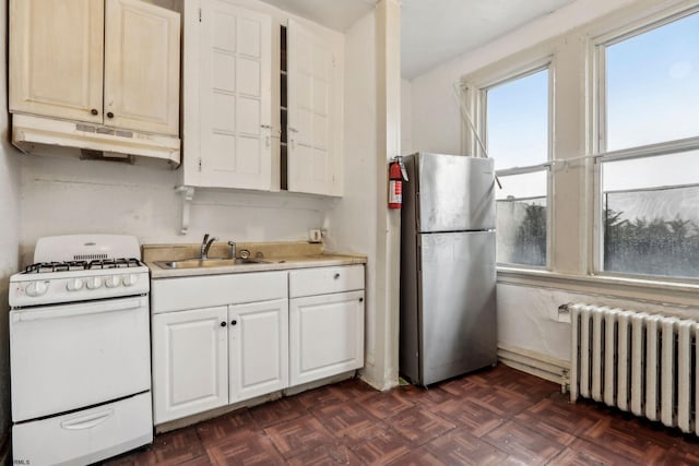 kitchen with radiator, stainless steel refrigerator, sink, dark parquet flooring, and white gas stove