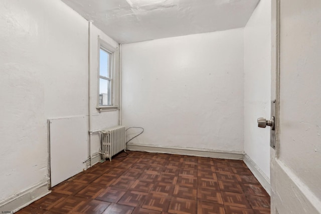 spare room featuring dark parquet flooring and radiator