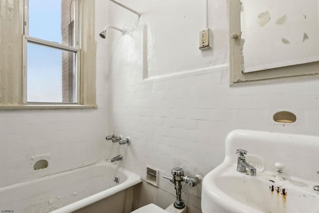 bathroom with tiled shower / bath combo, plenty of natural light, sink, and tile walls