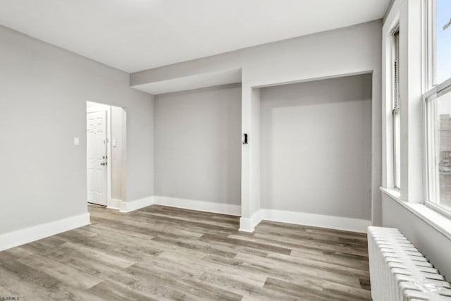 clothes washing area with radiator heating unit and light hardwood / wood-style flooring