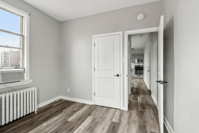 interior space featuring hardwood / wood-style flooring, radiator heating unit, and cooling unit