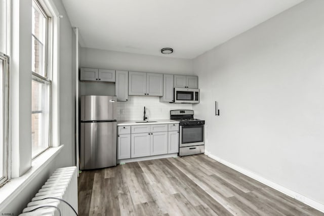 kitchen with plenty of natural light, appliances with stainless steel finishes, sink, and radiator heating unit