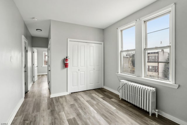 unfurnished bedroom featuring radiator, light hardwood / wood-style floors, and a closet