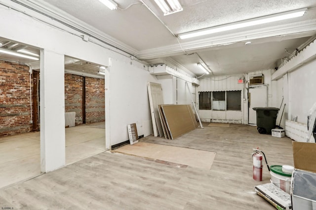 basement with light wood-type flooring, radiator heating unit, and brick wall