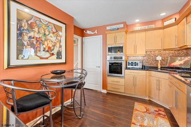 kitchen featuring dark wood-type flooring, light brown cabinetry, a breakfast bar area, stainless steel appliances, and decorative backsplash