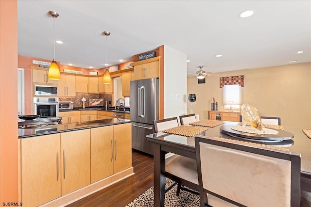 kitchen featuring appliances with stainless steel finishes, dark hardwood / wood-style floors, light brown cabinetry, decorative light fixtures, and sink