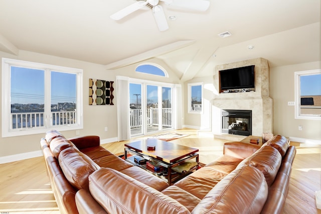 living room featuring a high end fireplace, vaulted ceiling, ceiling fan, and light wood-type flooring