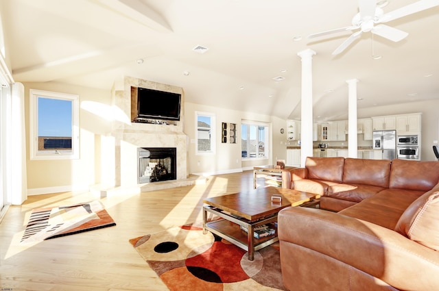 living room featuring ceiling fan, a fireplace, light hardwood / wood-style floors, and vaulted ceiling