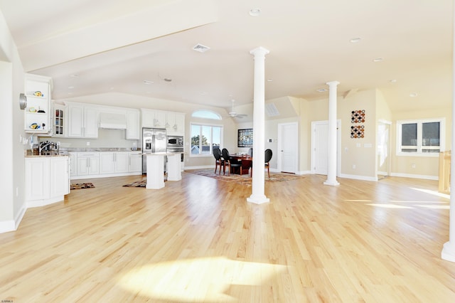 living room featuring vaulted ceiling, light wood-type flooring, and ornate columns