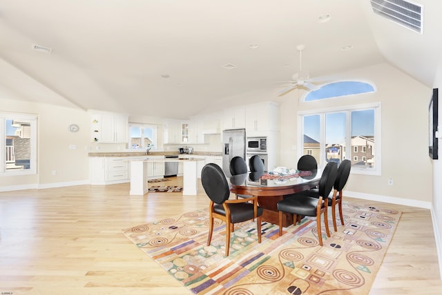 dining room featuring lofted ceiling, a wealth of natural light, ceiling fan, and light wood-type flooring