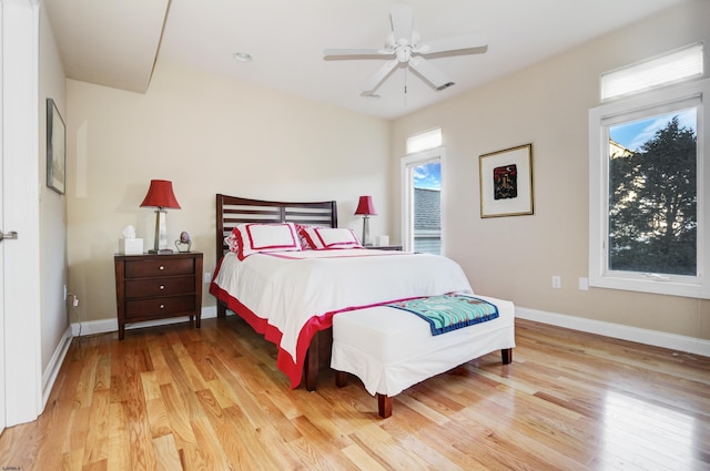 bedroom featuring ceiling fan, light hardwood / wood-style floors, and multiple windows