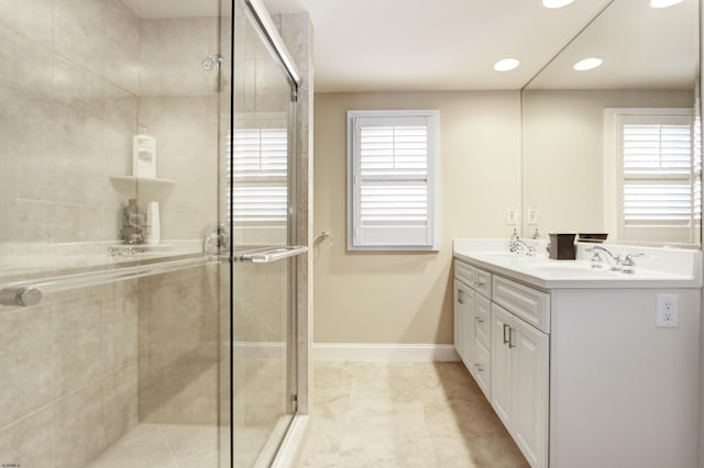 bathroom with vanity, a shower with shower door, and a wealth of natural light