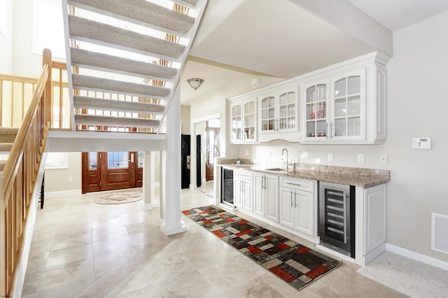 bar with beverage cooler, sink, and white cabinets