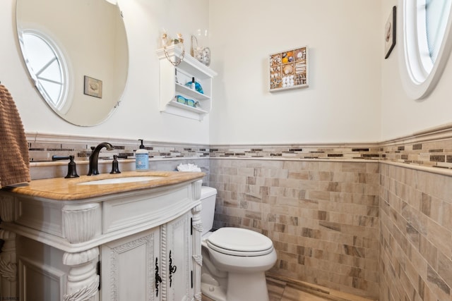 bathroom with vanity, tile walls, and toilet