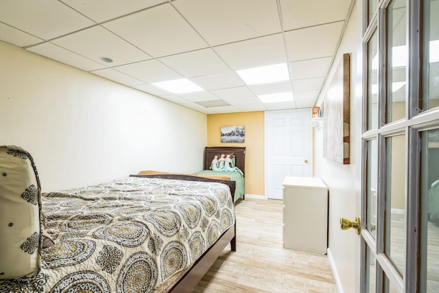 bedroom with a paneled ceiling and light hardwood / wood-style flooring