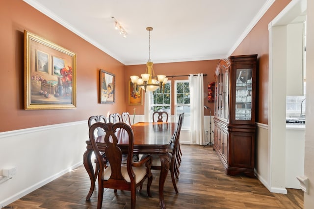 dining area with dark wood-type flooring, ornamental molding, and a chandelier