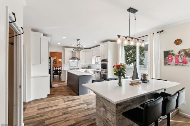 kitchen featuring pendant lighting, white cabinetry, a kitchen island, stainless steel appliances, and a kitchen bar