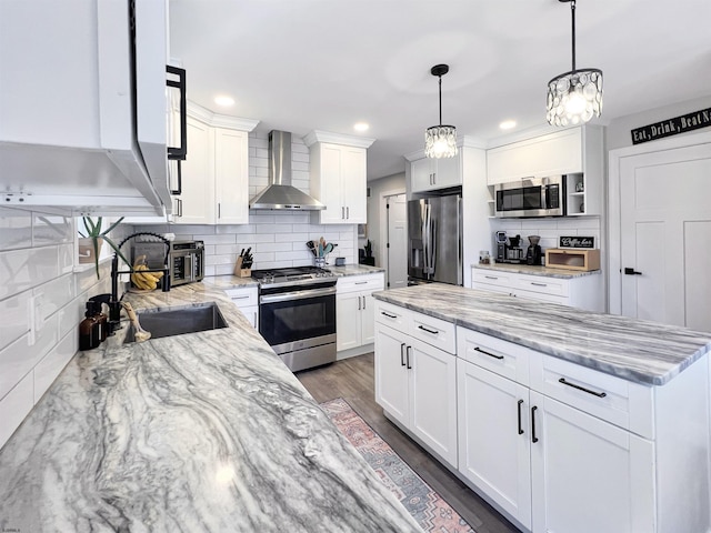 kitchen with white cabinetry, decorative light fixtures, stainless steel appliances, and wall chimney exhaust hood