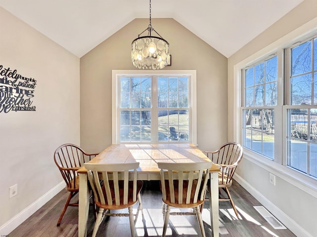 dining space with lofted ceiling, dark wood-type flooring, and an inviting chandelier