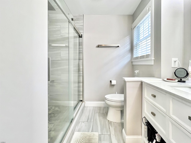 bathroom featuring vanity, a shower with shower door, and toilet