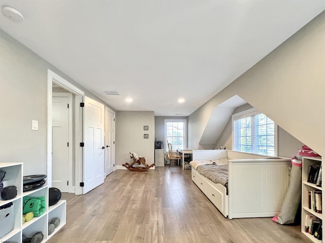 bedroom with lofted ceiling and light wood-type flooring